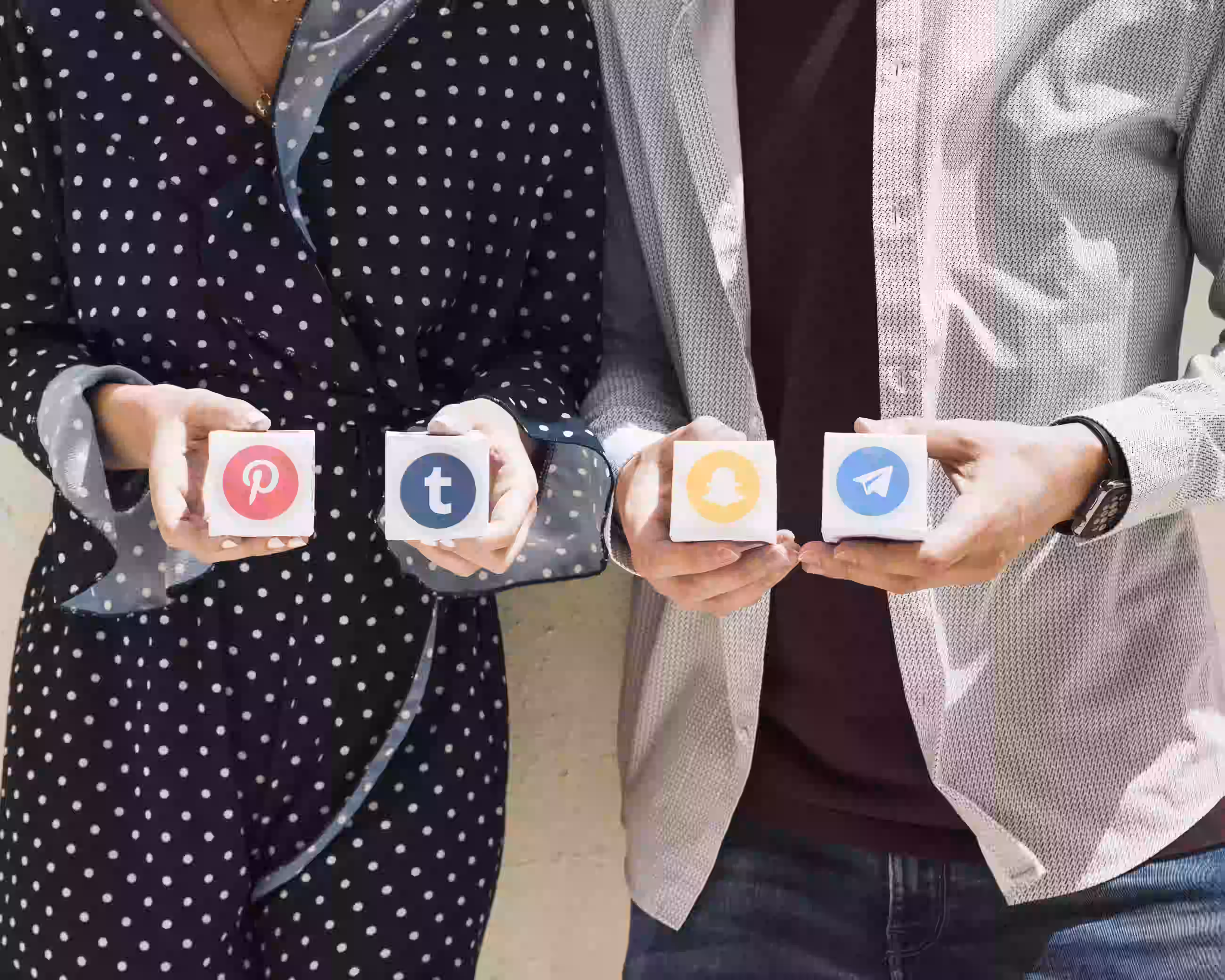 Два человека держат иконки социальных платформ, включая Pinterest, Tumblr, Snapchat и Telegram